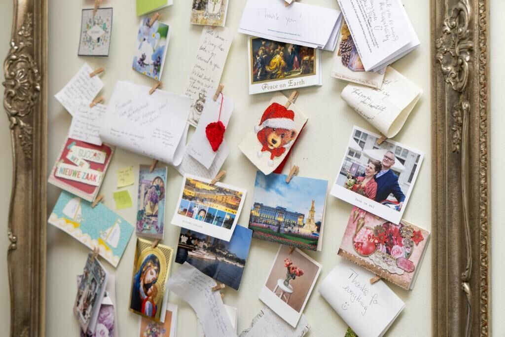 Eine Sammlung verschiedener Postkarten und Notizen, die an einer Wand befestigt sind, wobei einige Bilder und Text zeigen.