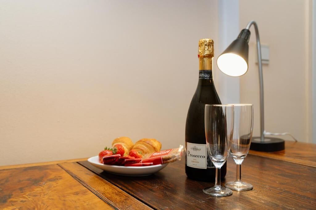 Une bouteille de vin Prosecco, deux verres et une assiette avec des pâtisseries et des fraises, le tout posé sur une table en bois.