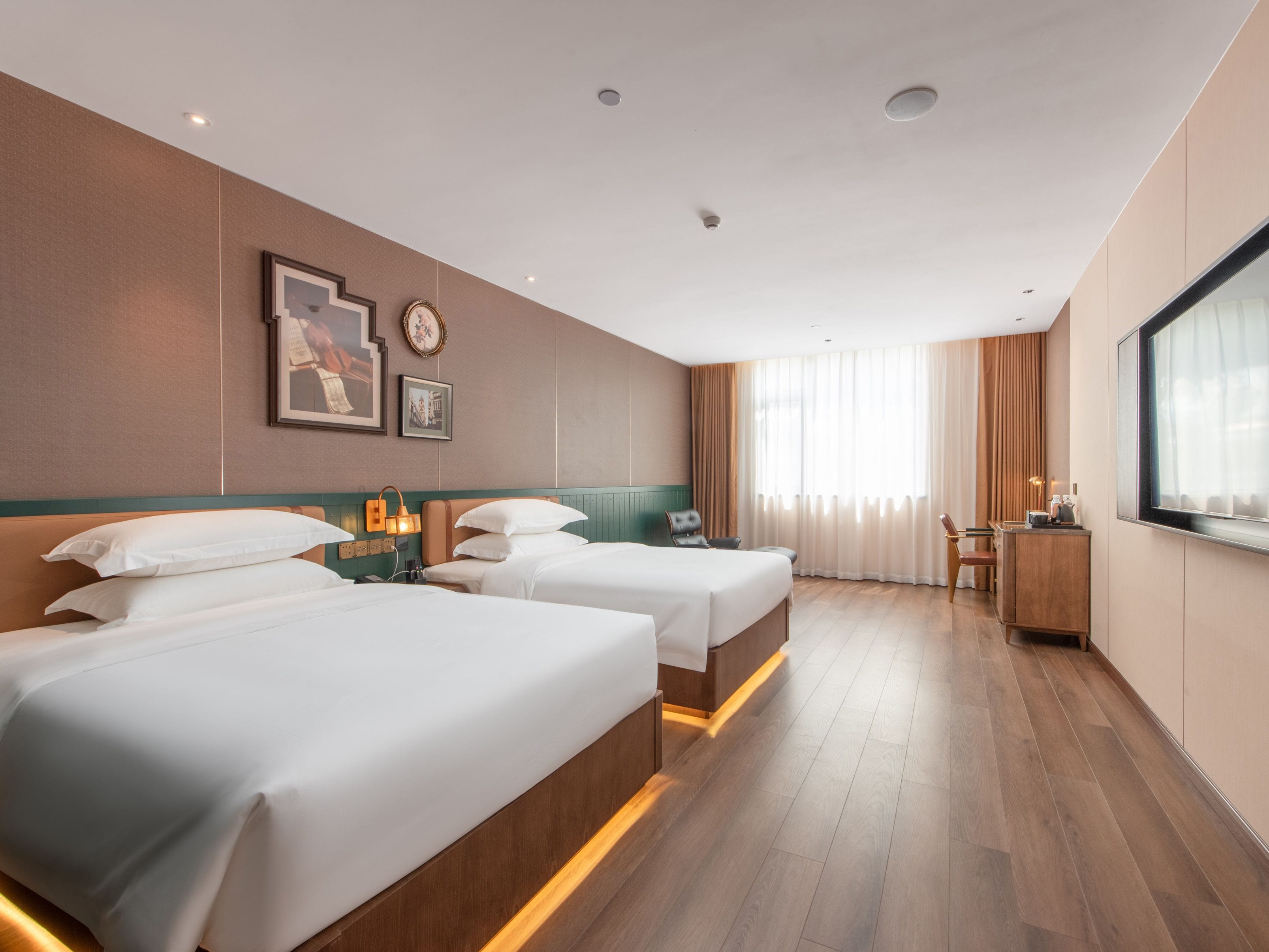 Habitación de hotel con dos camas, un escritorio, una silla y un ventanal grande.
