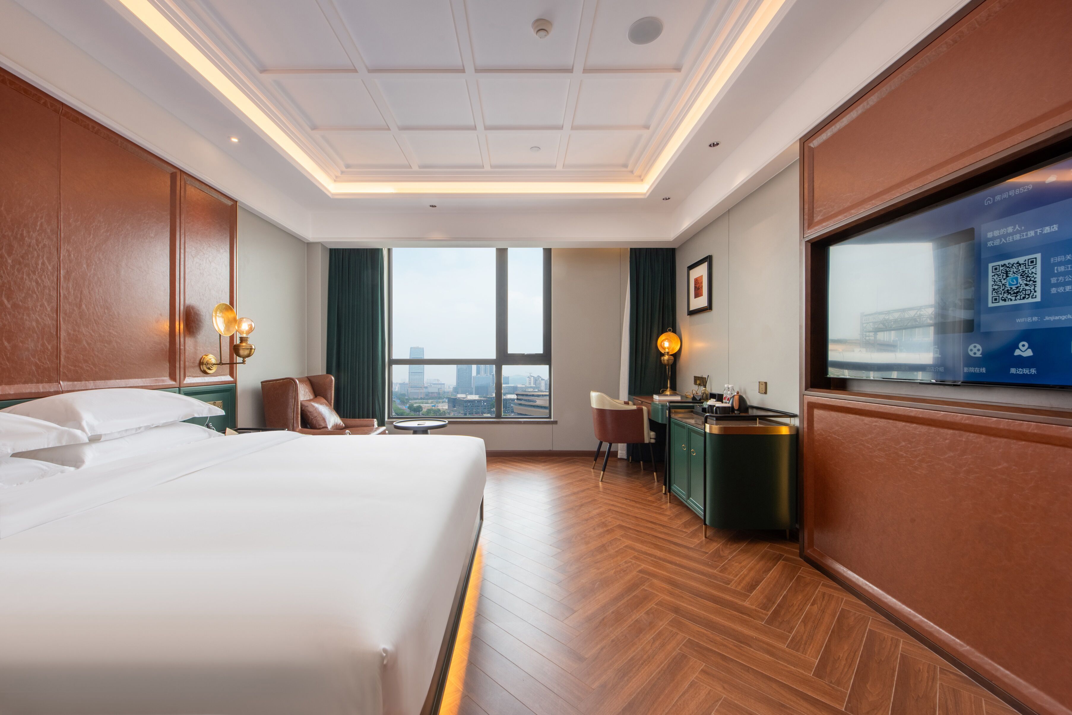Hotelkamer met een groot bed, een bureau, een stoel, een televisie en uitzicht op de stad.