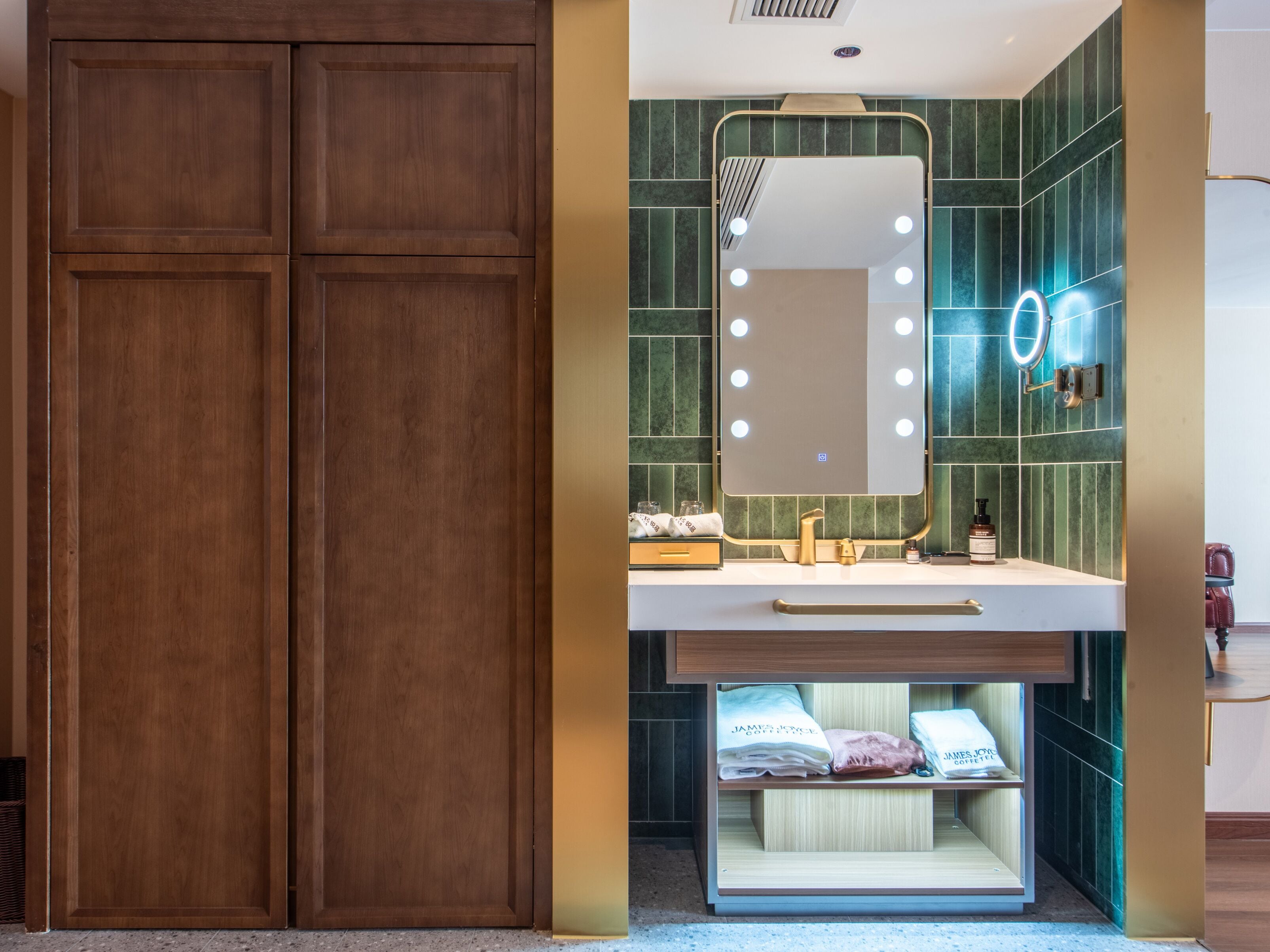 A bathroom with a vanity, mirror, and green tiled walls.