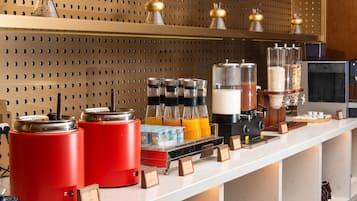 Una estación de café con varias máquinas de café, un espumador de leche y una variedad de granos de café y cartones de leche.