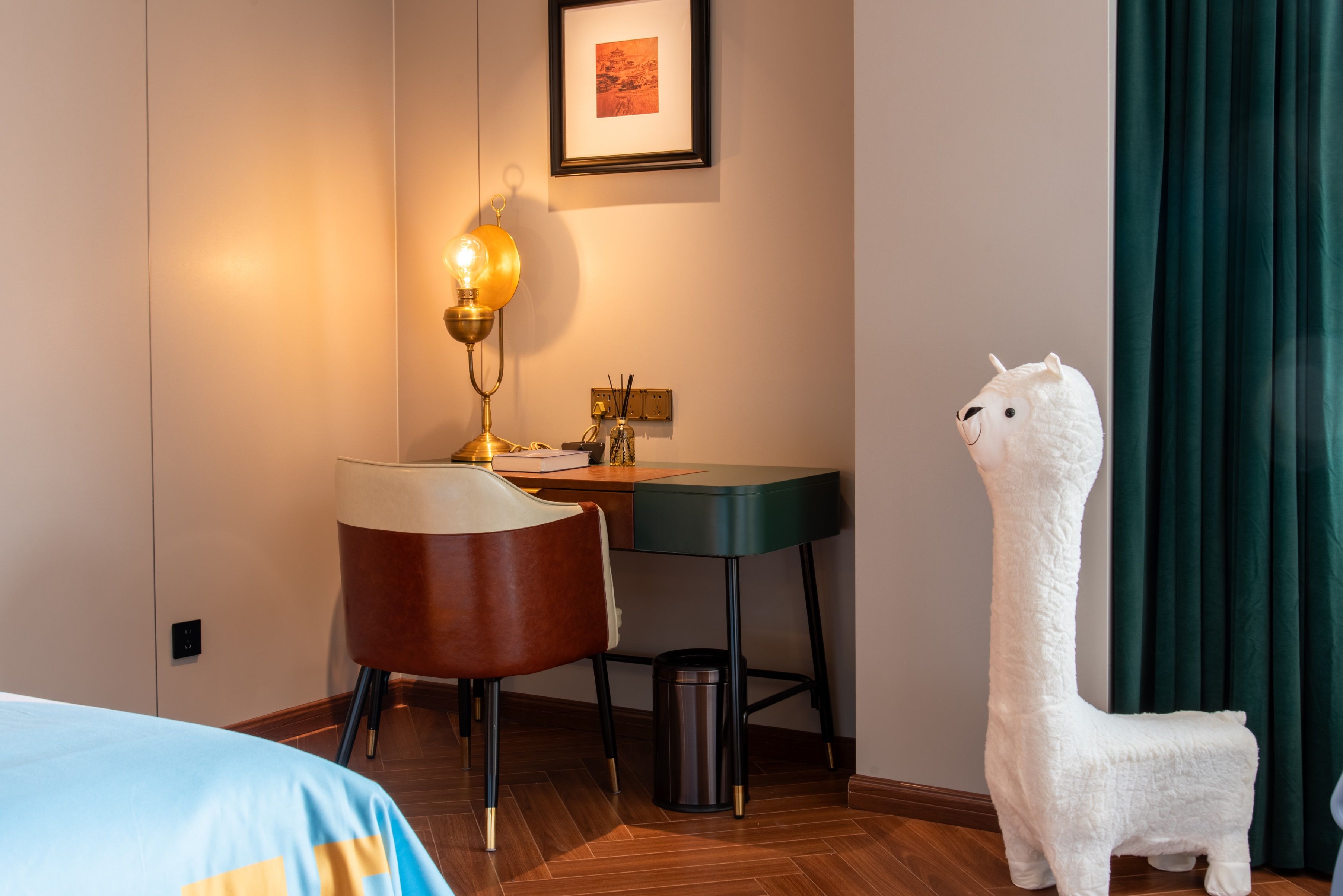A hotel room with a desk, chair, lamp, and a decorative white llama statue.