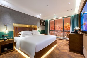 A hotel room with a large bed, a desk with a telephone, and a view of autumn leaves through the window. - ELITE James Coffetel Baiyun Wanda Plaza (Guangzhou)