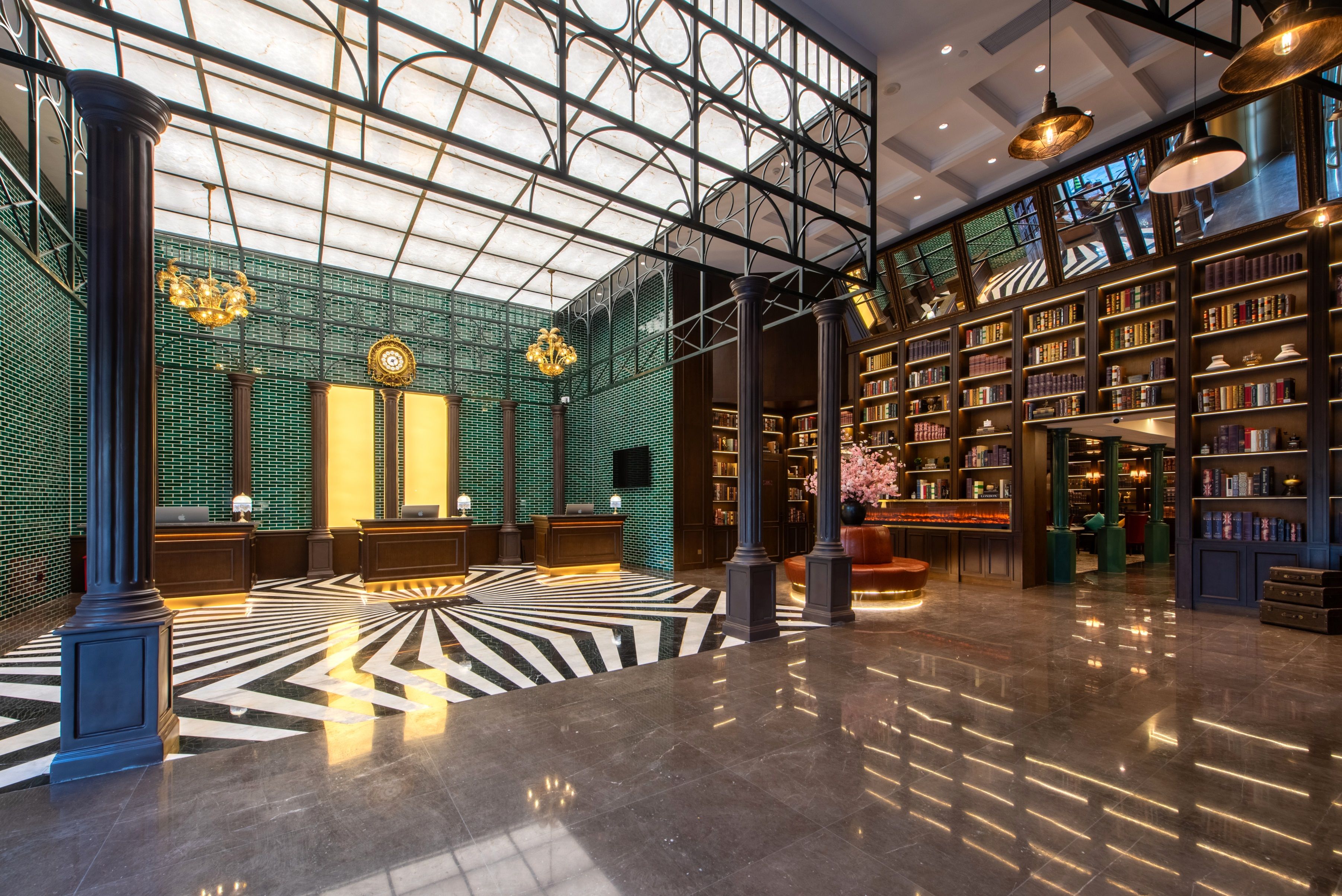 Een ruime lobby met een hoog plafond, een vloer met een zwart-wit patroon en een grote boekenkast gevuld met boeken.