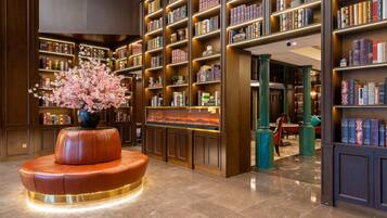Una biblioteca con estanterías, chimenea y un banco de cuero.