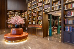 A library with bookshelves, a fireplace, and a leather bench. - ELITE James Coffetel Baiyun Wanda Plaza (Guangzhou)