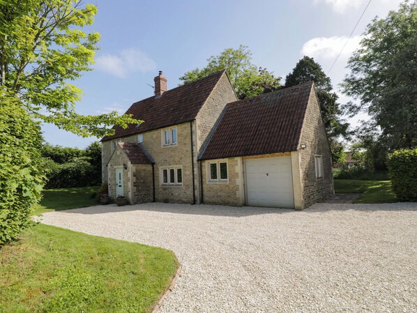 A two-story stone house with a gravel driveway and a garage. - The Paddocks (Chippenham)