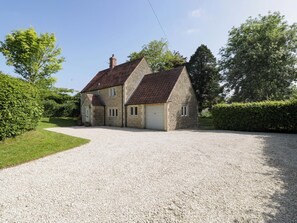 A two-story stone house with a gravel driveway and a garage. - The Paddocks (Chippenham)