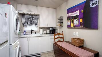 A compact kitchen with a refrigerator, sink, and a dining area with a table and chair.