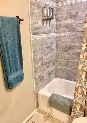 Baño con ducha, toallero y cortina de ducha.