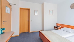 Una habitación de hotel con cama, escritorio y puerta.