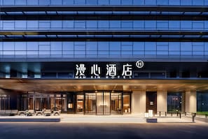 A modern hotel entrance with a glass facade and a sign reading 'MANXIN HOTEL'. - Manxin Hotel Anzhen Qiao Metro Station (Beijing)