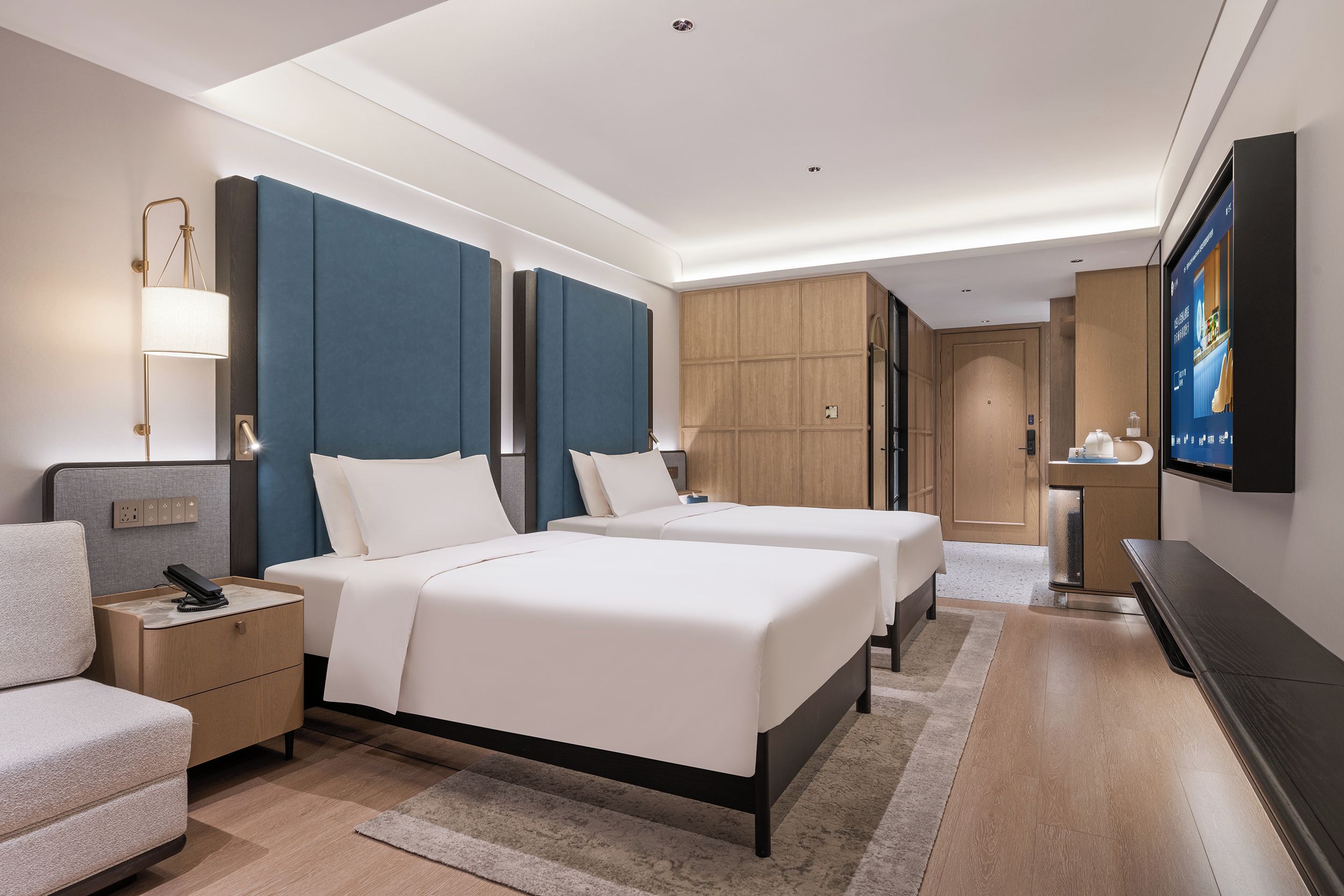 Une chambre d’hôtel avec deux lits, un bureau, une chaise, une télévision et une armoire.