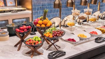 Un bufé con diversas frutas y postres.
