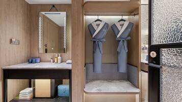 A modern bathroom with a wooden vanity, a mirror, and two robes hanging on hooks.