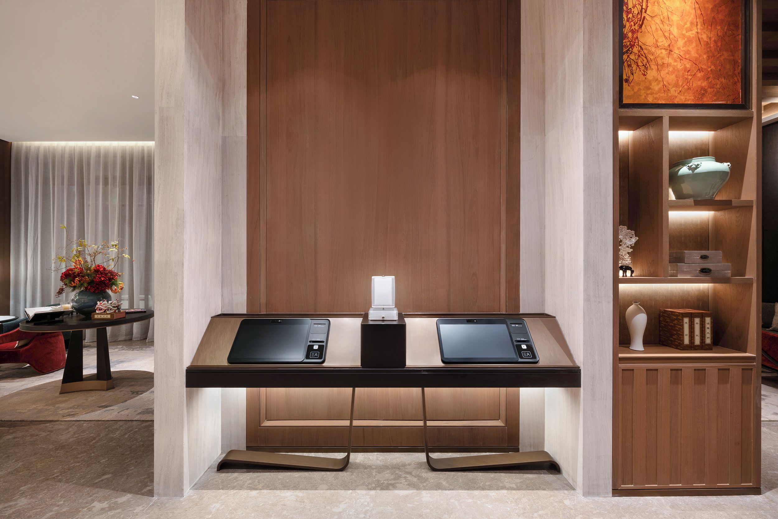 A modern hotel lobby with a reception desk, a decorative vase, and a small statue.