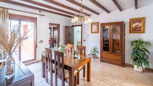 Un'area pranzo con arredi in legno, un lampadario e una pianta in vaso.
