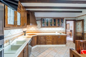 A kitchen with wooden cabinets, a central island, and a tiled backsplash. - Cubo's Urban Plaza Apartment / urban / air conditioning / terrace / free wifi (Alhaurín el Grande)