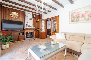 Ein Wohnzimmer mit Flachbildfernseher, Kamin, Sofa und Glastisch.