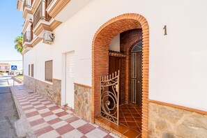 A building with a checkered pathway leading to an arched entrance with a metal gate. - Cubo's Urban Plaza Apartment / urban / air conditioning / terrace / free wifi (Alhaurín el Grande)