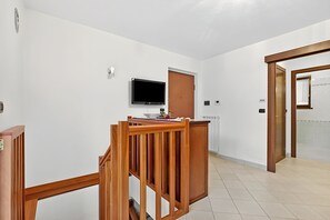 Ein Zimmer mit einem Holztisch, einem flachbildfernseher an der Wand und einer Tür zu einem anderen Raum.