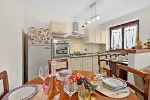 Eine kompakte Küche mit Essbereich, ausgestattet mit Kühlschrank, Backofen und einem Fenster mit Vorhängen.