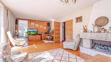 A spacious living room with a television, wooden furniture, a fireplace, and a view of the outdoors.