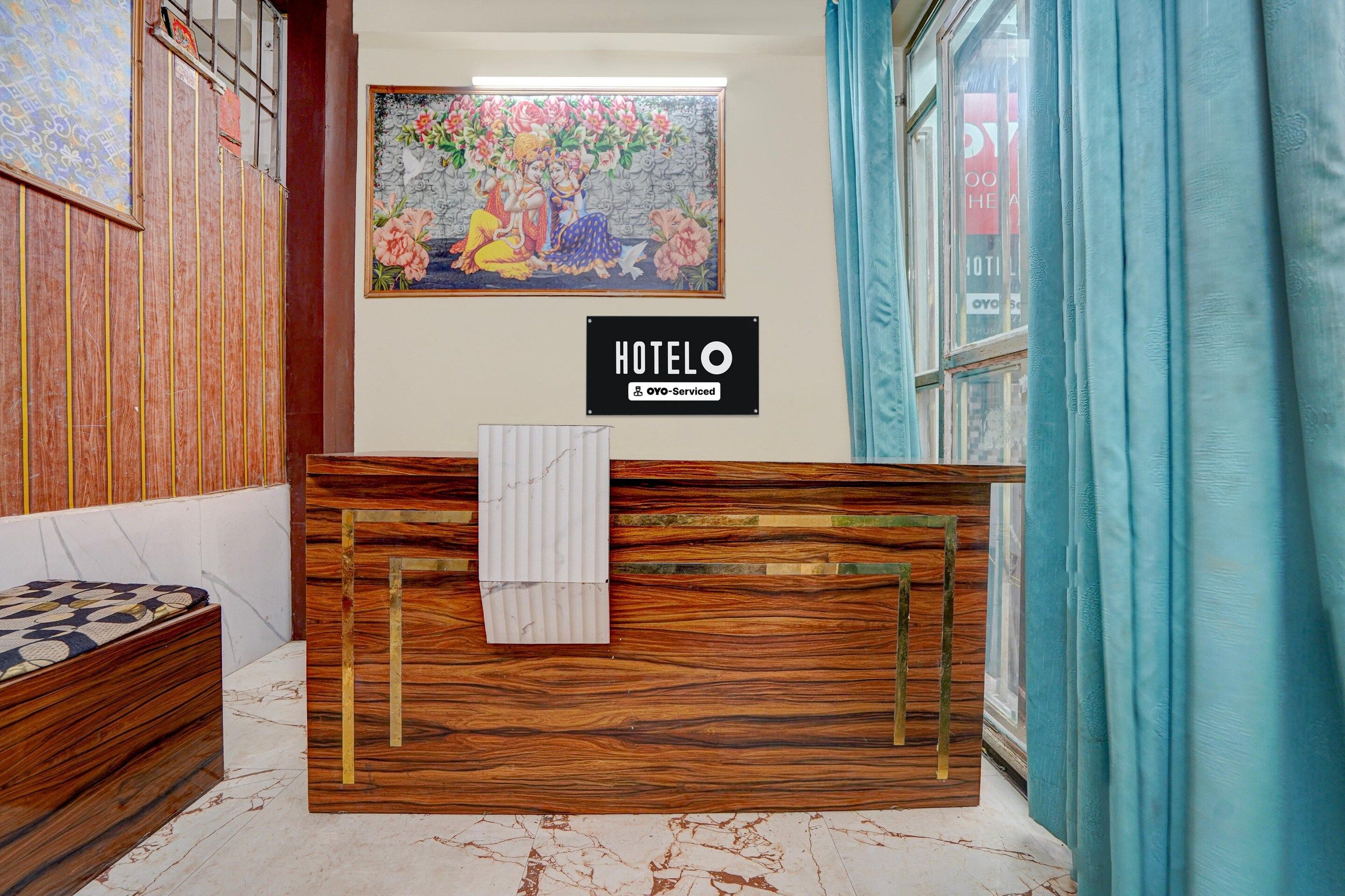 Un comptoir d’accueil d’hôtel avec un revêtement en bois, une œuvre d’art florale encadrée au-dessus, et une enseigne indiquant que l’établissement est géré par OYO.