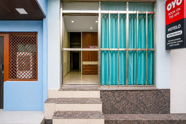 A hotel entrance with a reception desk, a sign indicating booking via an app, and a guest house. - Classic Mathura Railway Junction (Mathura)