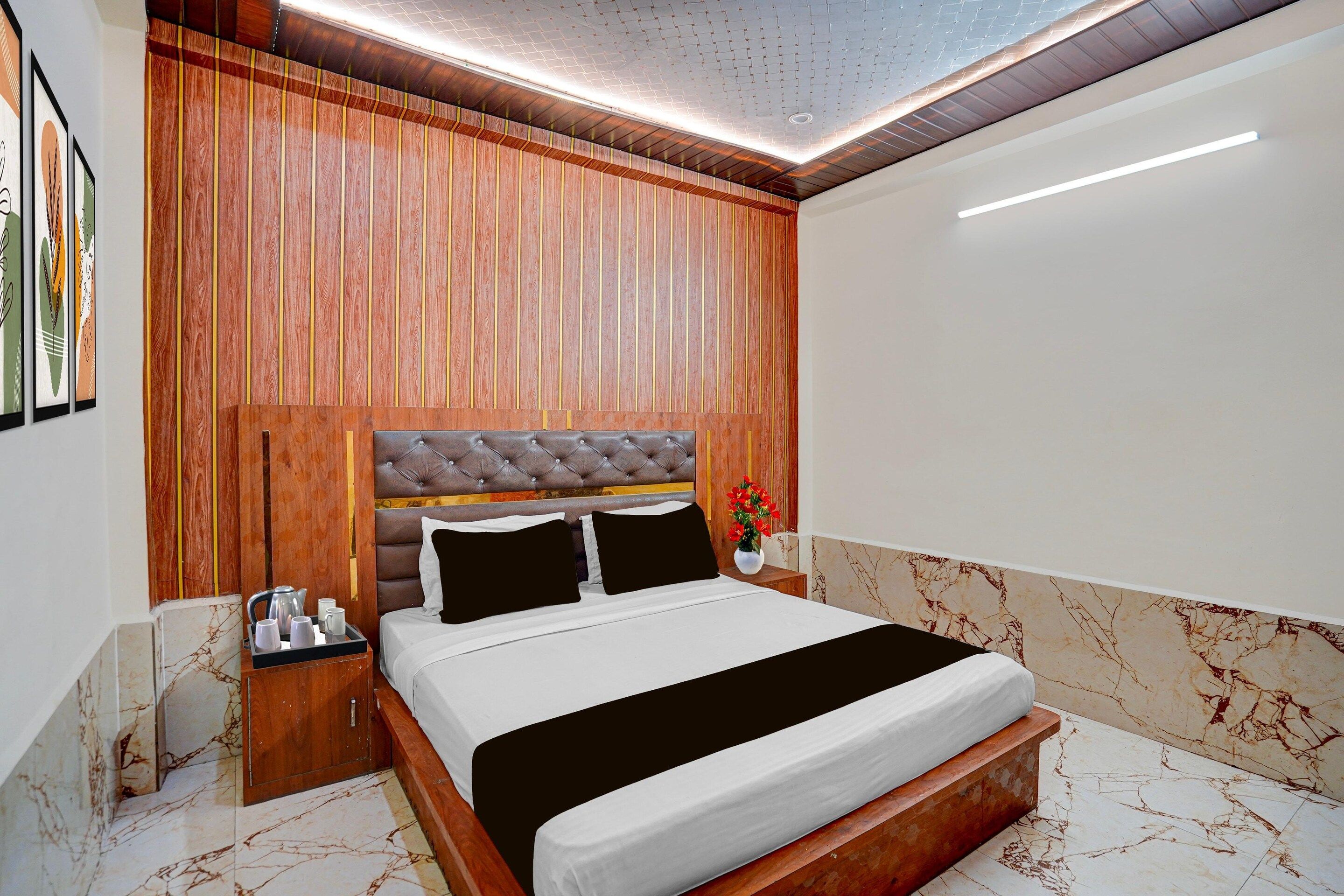 Una camera da letto moderna con una testiera in legno, un letto con biancheria a righe bianche e nere, un comodino con un bollitore e un vaso con fiori.