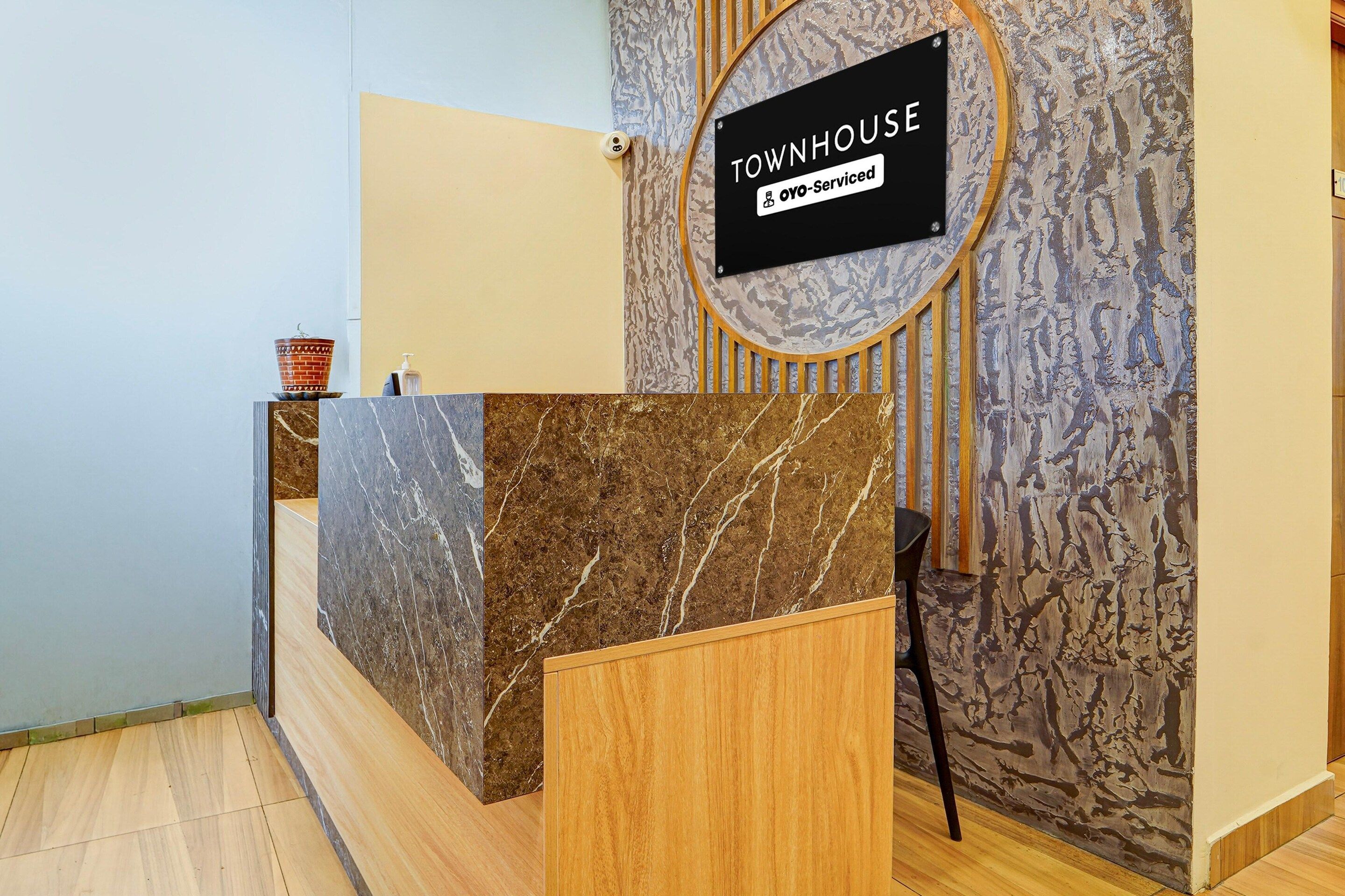 A reception desk with a marble top, a wooden counter, and a sign indicating it's serviced by oyo.