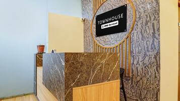 A reception desk with a marble top, a wooden counter, and a sign indicating it's serviced by oyo.