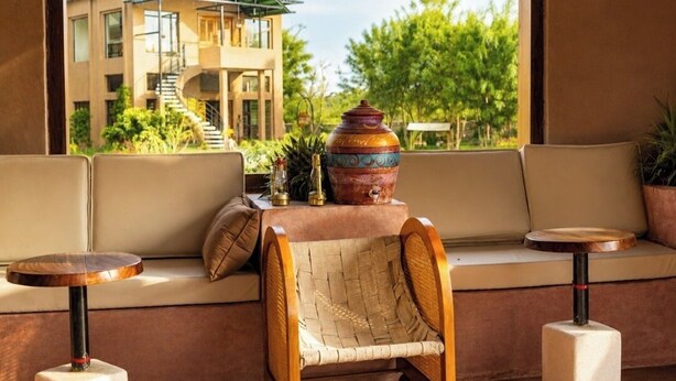 A seating area with a woven chair, two small round tables, and a decorative pot on a table.