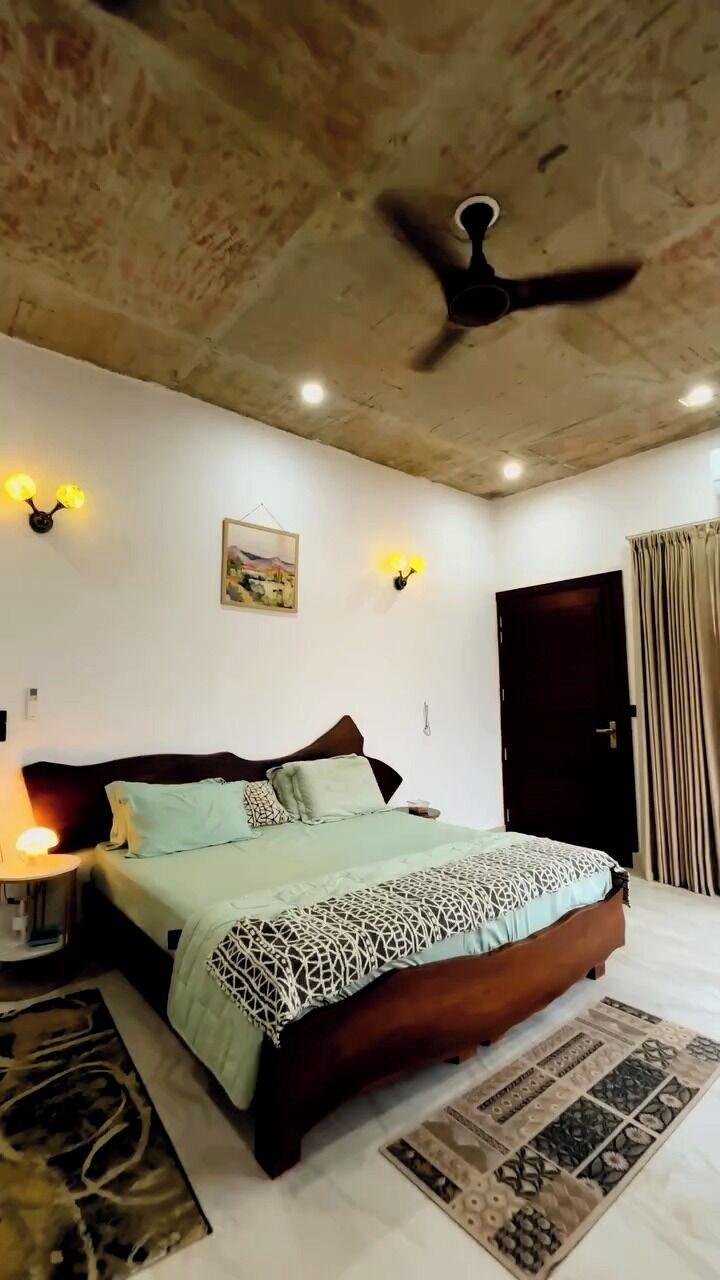 Un dormitorio con cama, ventilador de techo, luces empotradas en la pared y una puerta.