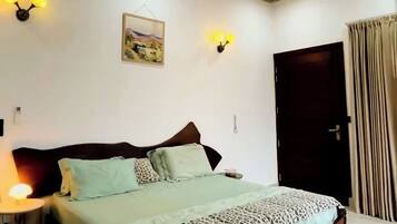Un dormitorio con cama, ventilador de techo, luces empotradas en la pared y una puerta.
