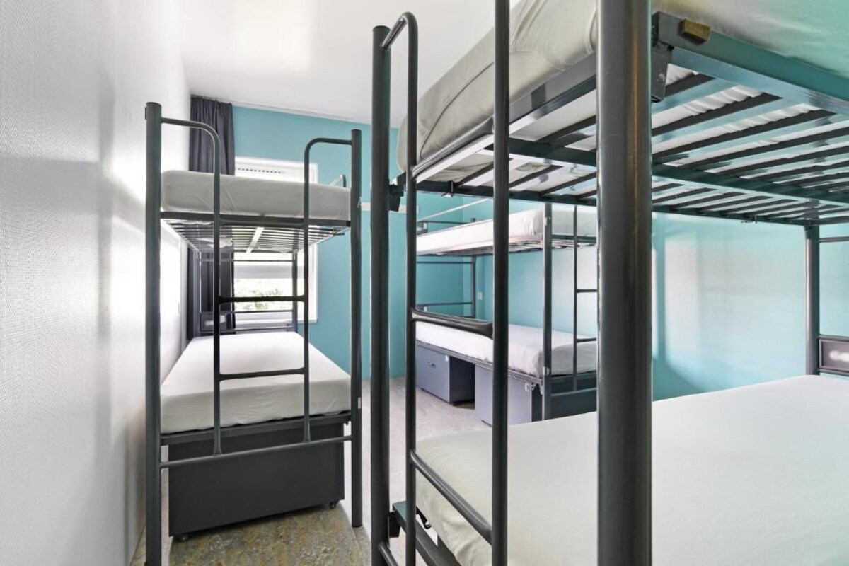 A bunk bed room with a window, a desk, and a chair.
