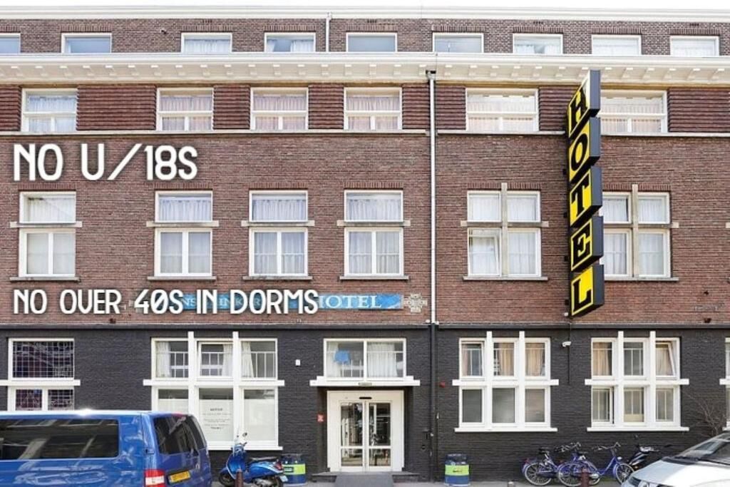 A two-story building with a sign indicating 'NO U/18S' and 'NO OVER 40S IN DORMS HOTEL'.