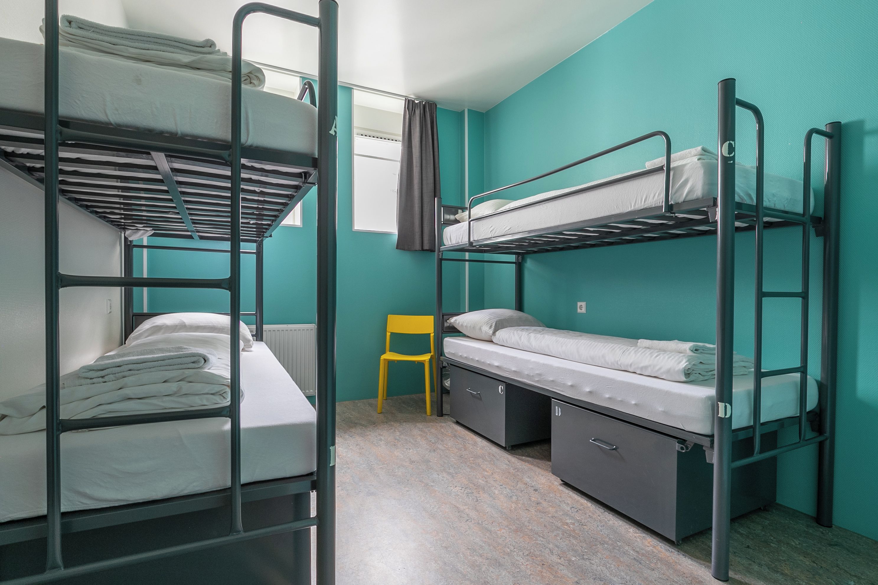 A bunk bed room with a small chair and a radiator.