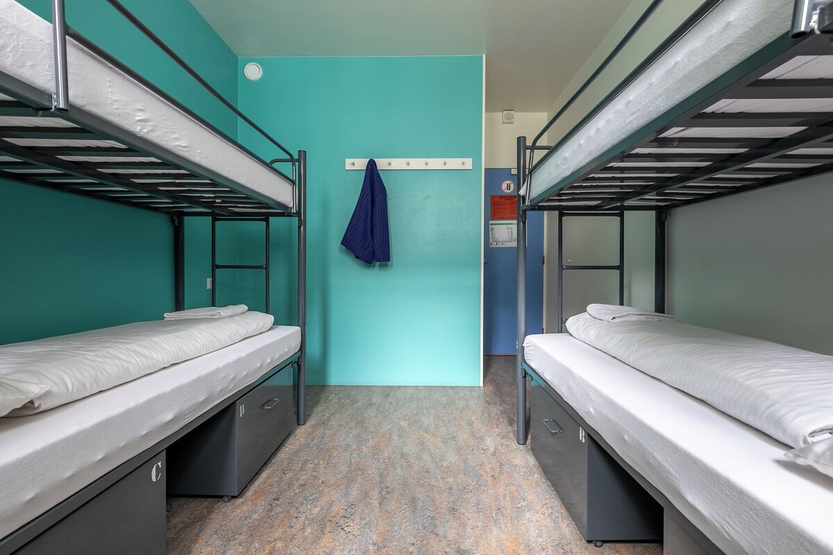 A bunk room with two beds, a towel rack, and a door with a sign.