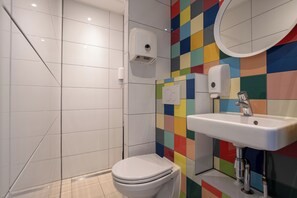 A bathroom with a white toilet, a sink, and a mirror. - Hans Brinker Hostel Amsterdam (Amsterdam)