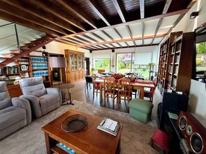 Un salón espacioso con una mesa de comedor, asientos cómodos, una estantería y vistas al exterior.