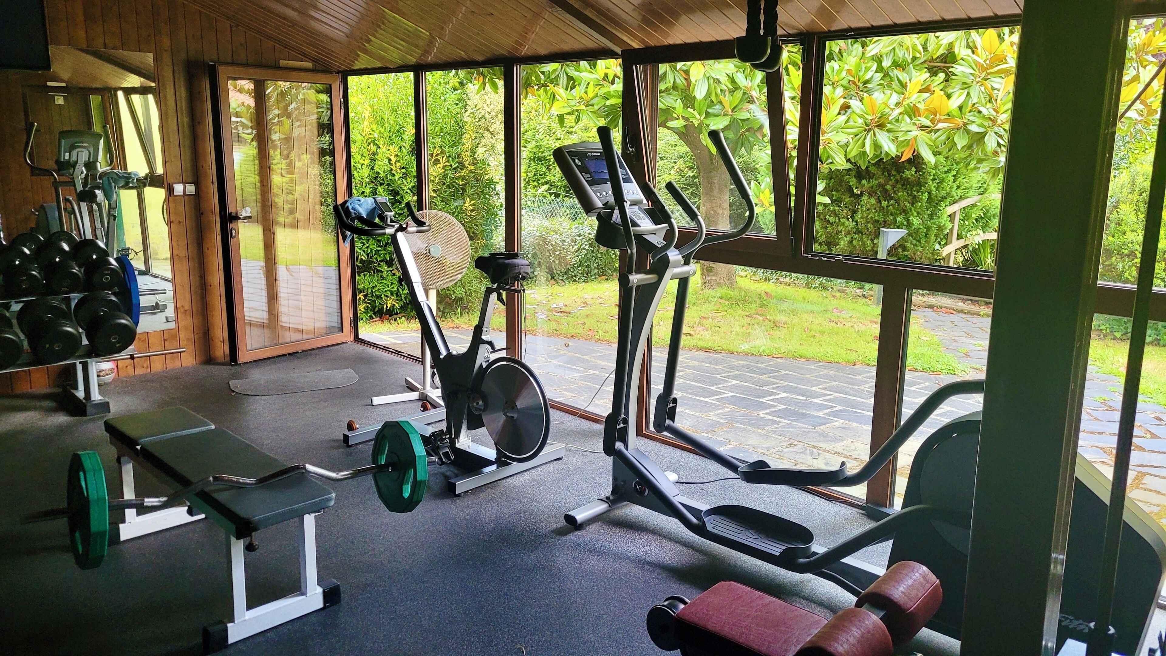 Una sala de gimnàstica amb equipament d'exercici, una banca i una pilona de peses.