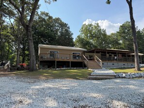 A two-story cabin with a deck and outdoor seating area, surrounded by trees.