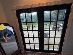 A black-framed glass door leading to a wooden deck with outdoor furniture.