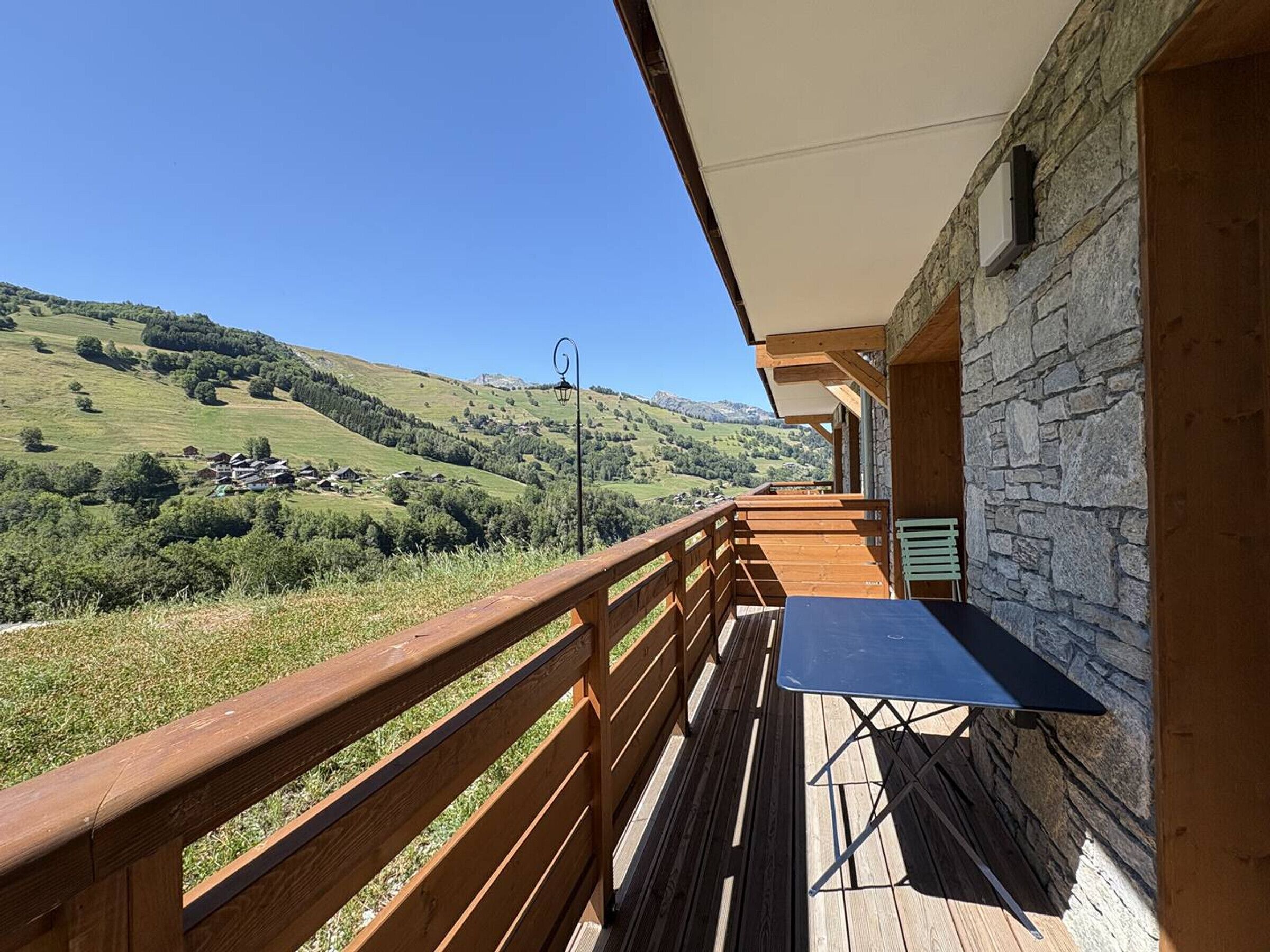 A wooden deck with a table and chairs, overlooking a mountainous landscape.