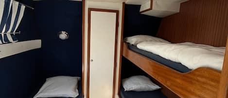 A compact cabin with two bunk beds, a small window with curtains, and a door.