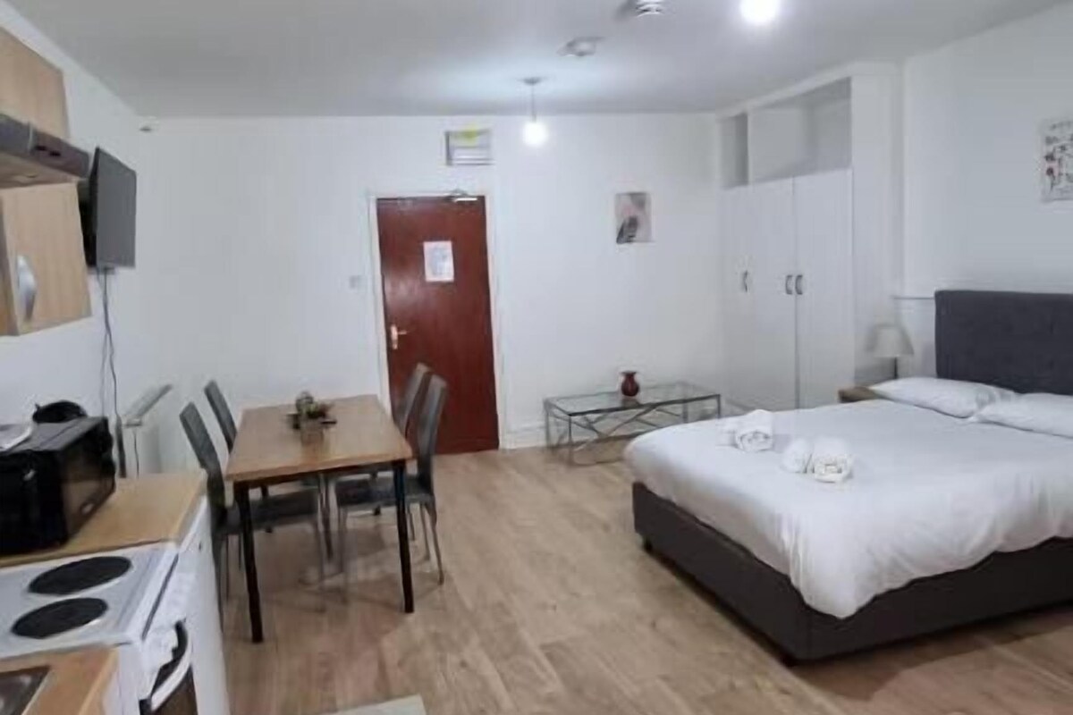 Ein gemütlicher Raum mit Küchenzeile, Essbereich und einem Bett.