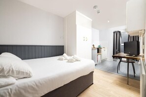 Ein Hotelzimmer mit einem Bett, einem Schreibtisch mit Computer und einem Fernseher.