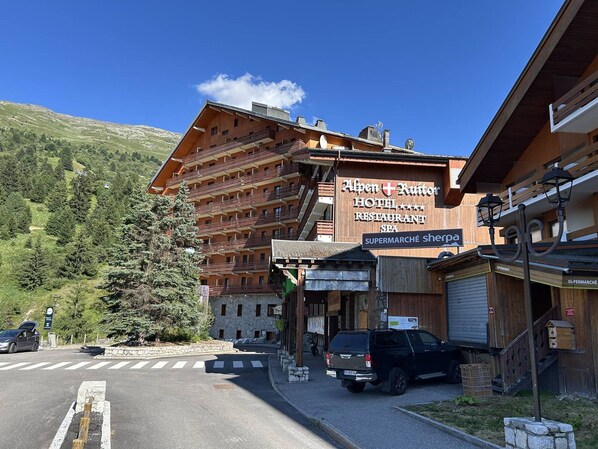 Um hotel com vários andares, um letreiro para restaurante e vista para uma montanha.